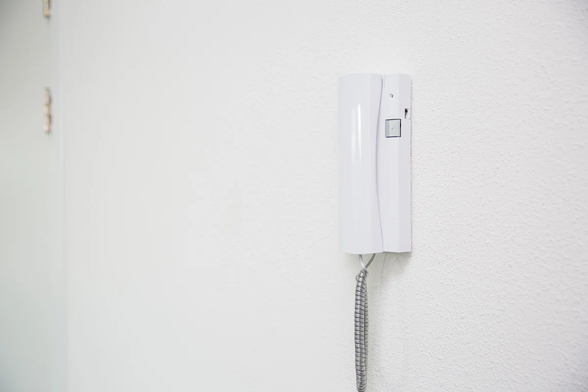 Witte intercom aan de muur in een helder verlichte gang op de Laan van ’s-Gravenmade.